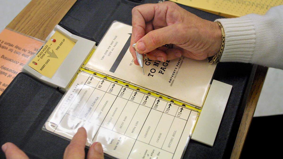 A Broward County poll worker demonstrates how to make a proper punch to avoid hanging chads in the voting process.