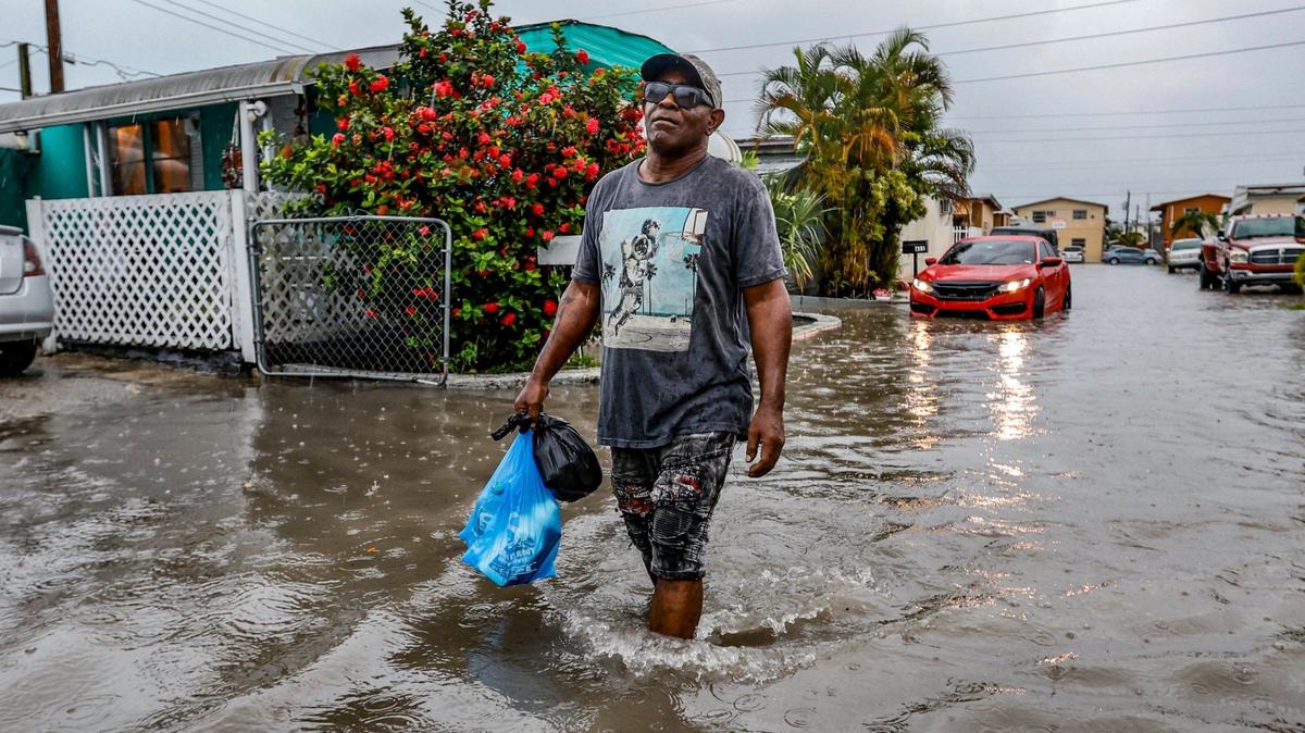 Mires Aguenar walks through flooded street at Holiday Acres Mobile Home Park in Hialeah, Florida on Wednesday, June 12, 2024.