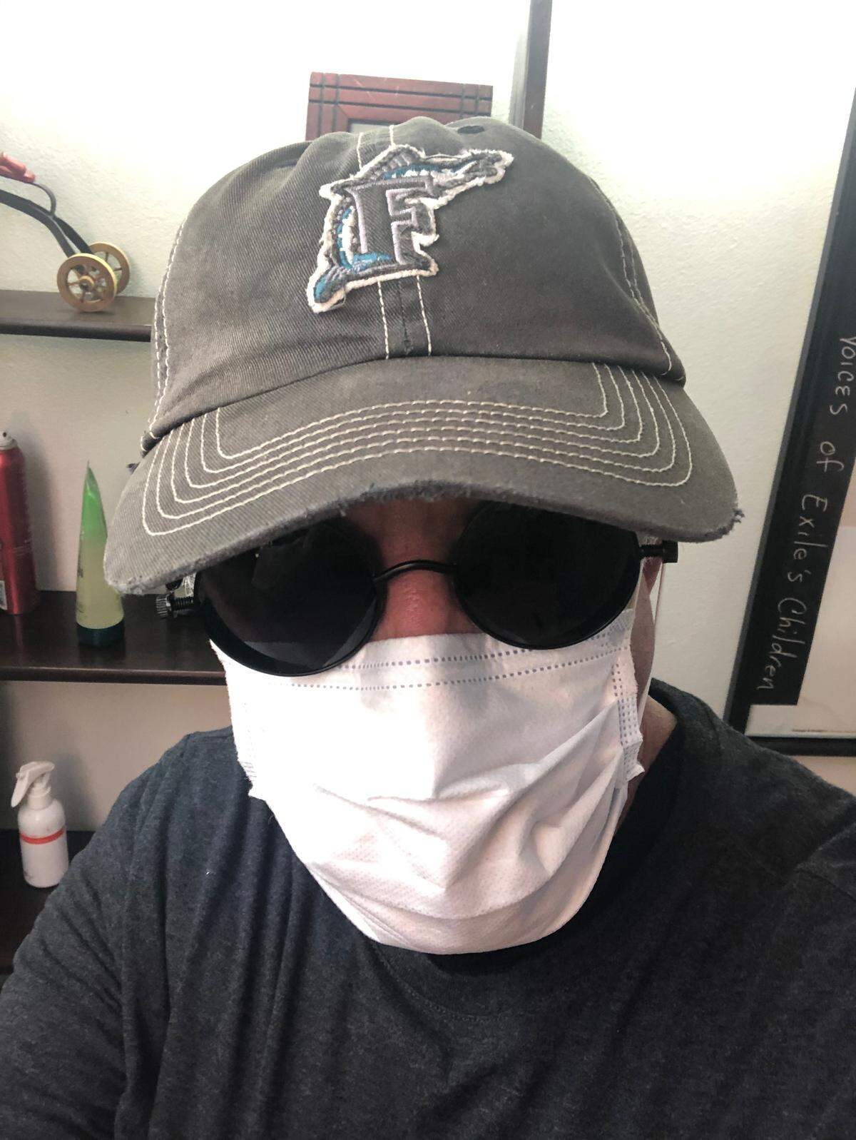 Hairdresser Manolo Portuondo dons a surgical mask and gloves, glasses and a cap to cut hair during the coronavirus pandemic.