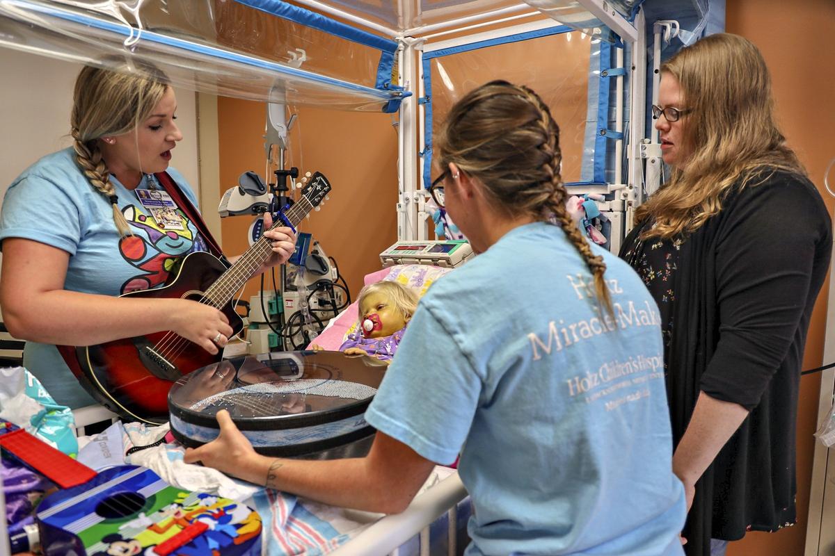 Music therapist Stephanie Epstein, left, stands bedside by Elizabeth “Lizzy” Foley, 2, who suffers from Alagille Syndrome, and sings a song from “Frozen” while her music therapist intern, Hannah Sellers, and Elizabeth’s mother, Amy Foley, assist in therapy on Tuesday, October 1, 2019, at Holtz Children Hospital in UM Jackson Medical Center in Miami.