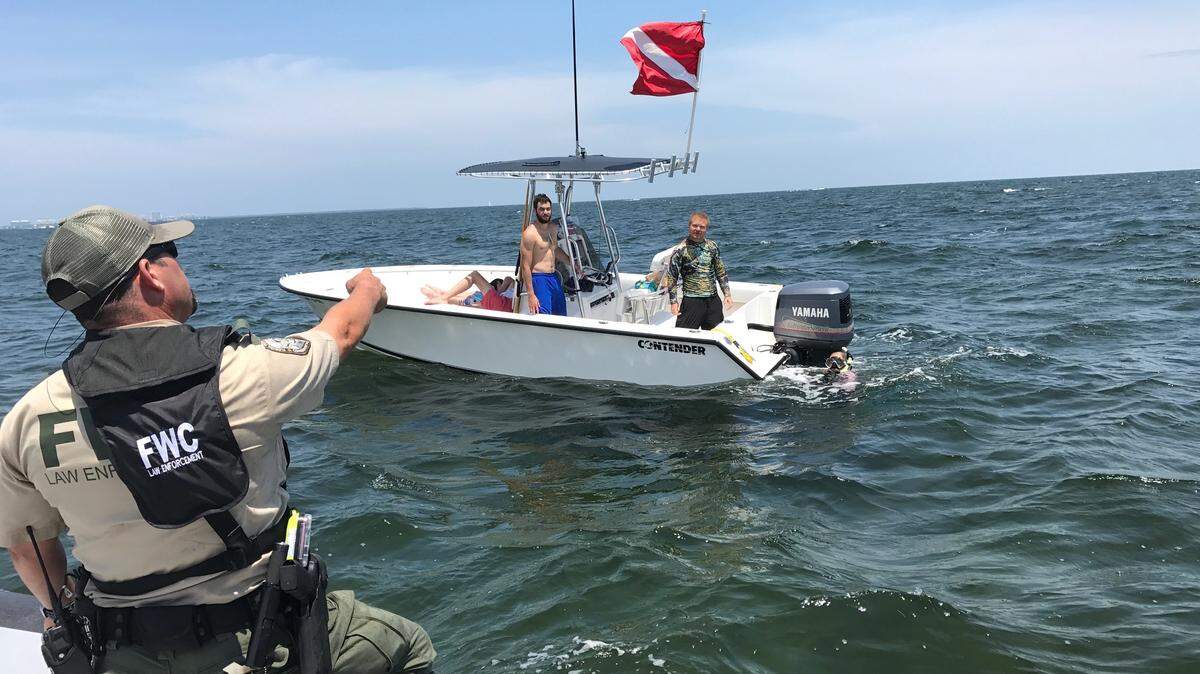 Guillermo Cartaya, agente de la FWC pide a un buzo que suba a su barco para inspeccionar la embarcación en busca de cualquier infracción el 25 de julio de 2018, el primer día de la minitemporada de langostas de dos días.