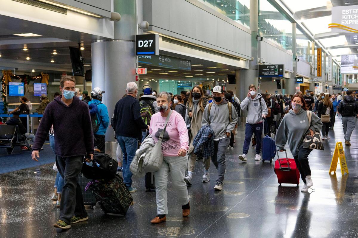 Travelers crowd the halls as they walk to their terminals at Miami International Airport in Miami, Florida in this Nov. 23, 2021 file photo.