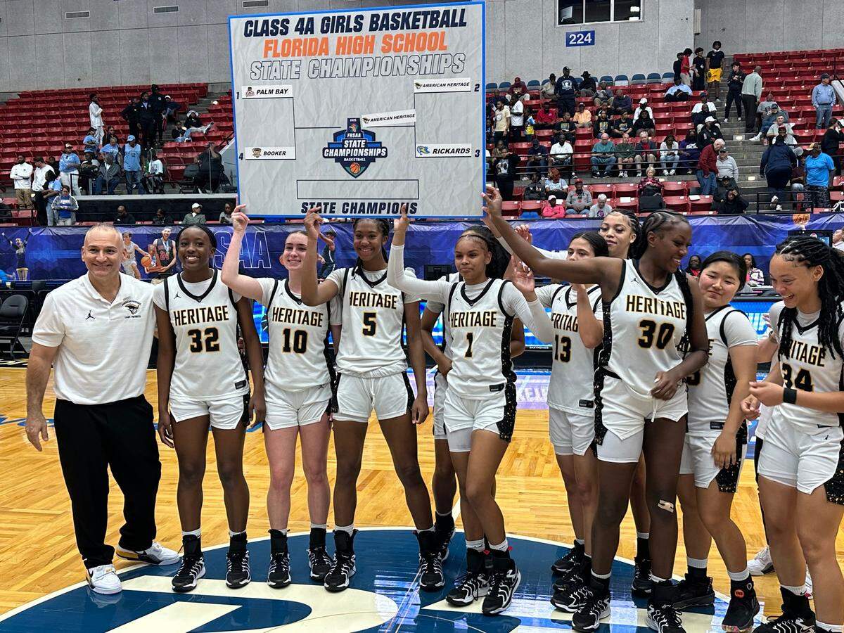 The American Heritage girls’ basketball team lifts up a cutout of the Class 4A state championship bracket after it defeated Tallahassee Rickards in a semifinal on Tuesday at the RP Funding Center in Lakeland, Fla.