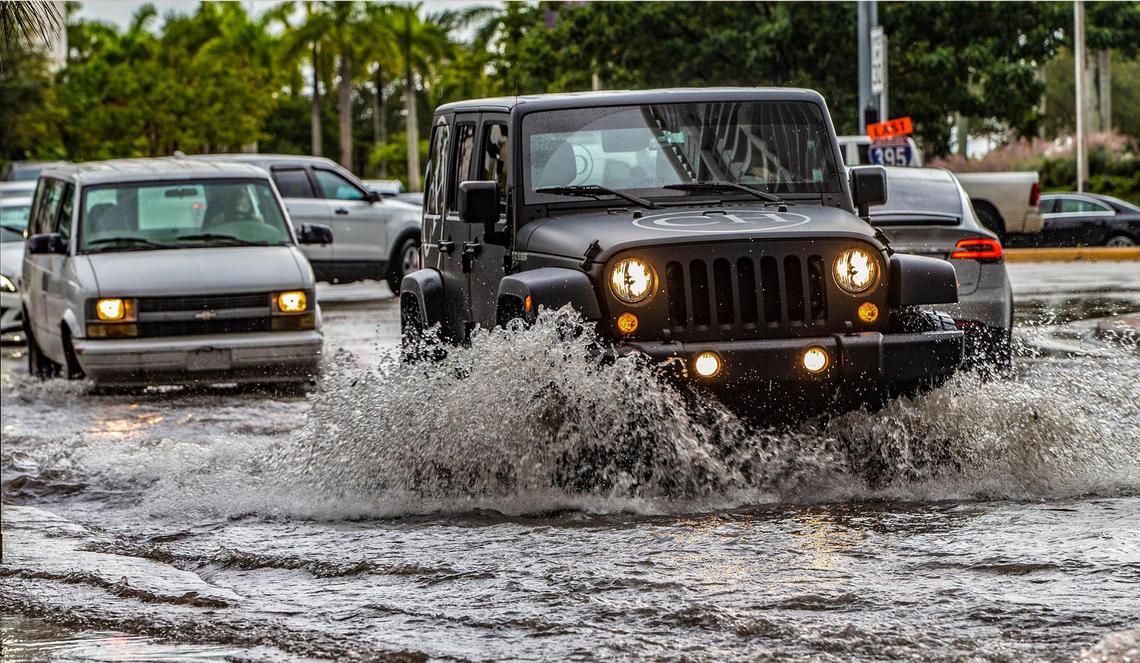 Cars drive through a flooded street at Northeast 11th  Street and Biscayne Boulevard in Miami during heavy rains and king tides on Nov. 5, 2021.