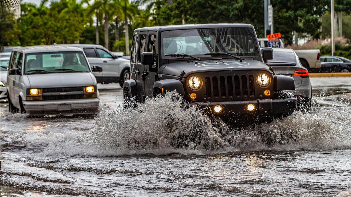 Cars drive through a flooded street at NE 11 Street and Biscayne Boulevard in downtown as flooding rains and king tides drench South Florida streets on Friday, Nov. 5, 2021.