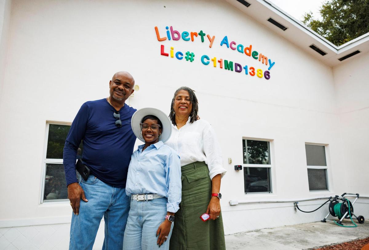 Monique Brazier, center, and her parents, Sarah and Maurice, pose in front of Liberty Academy on Friday, Nov. 15, 2024, in Liberty City.