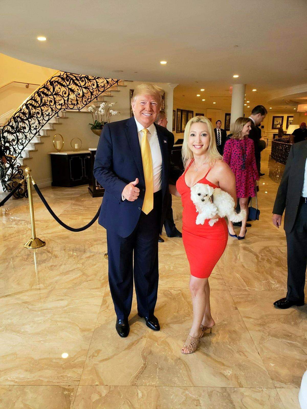 Christine Deckert poses with President Donald Trump at the Trump Doral resort on June 19, 2019. Her Maltese dog, Baby, was yelping as the president passed through the lobby. He paused and agreed to the photo.