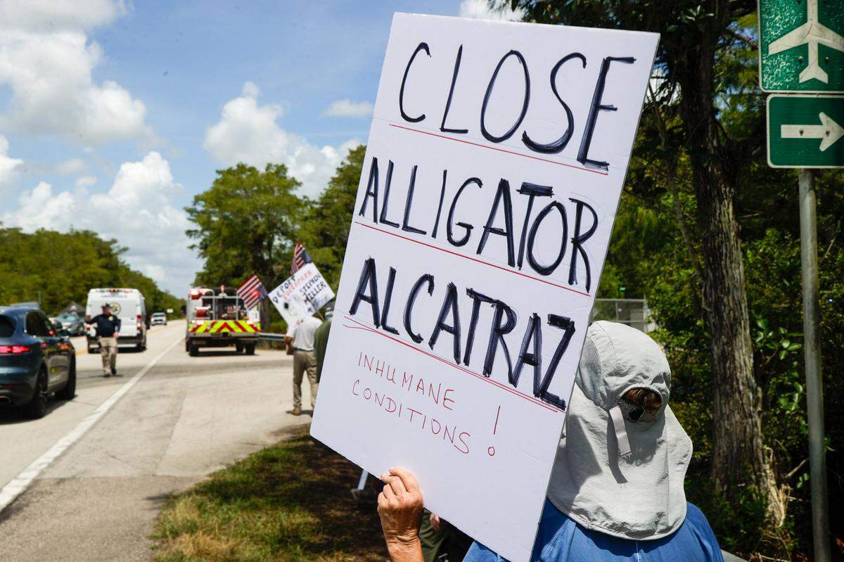 Protesters hold up signs outside of Alligator Alcatraz on Saturday, July 12, 2025 in Ochopee.