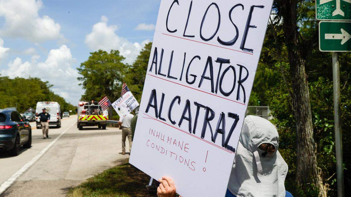 Protesters hold up signs calling for the closing of Alligator Alcatraz in the Everglades.