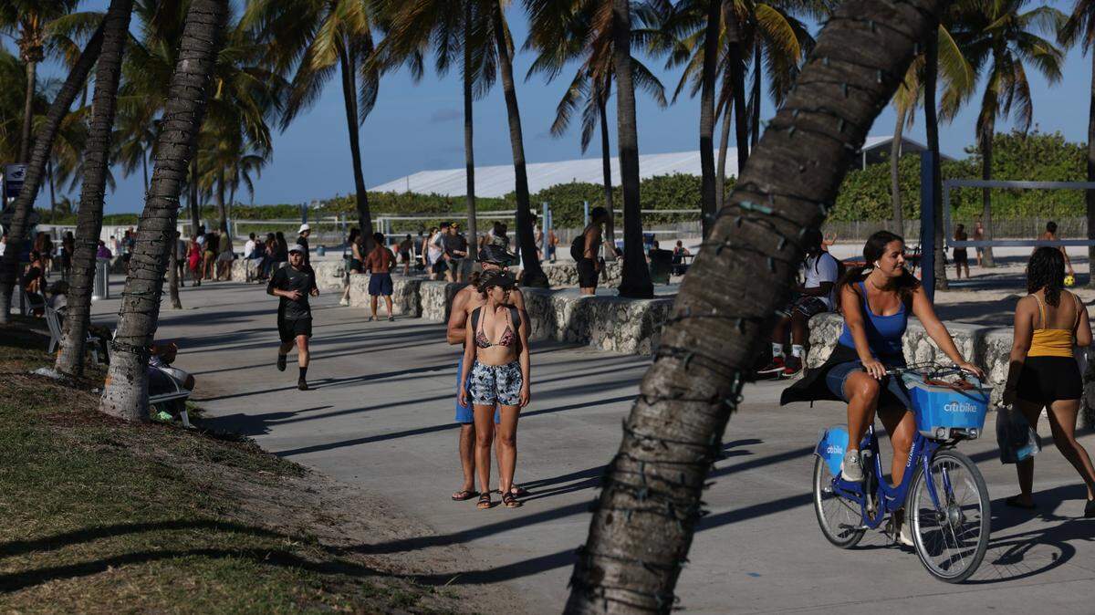 People walk along the sidewalk in Miami Beach during spring break on Sunday, March 26, 2023.