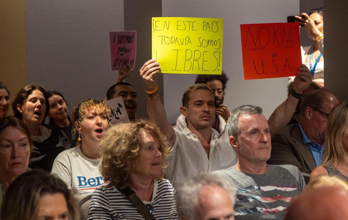 Miami Beach resident Phillip Carter holds up a protest sign at a Miami Beach City Commission meeting on Wednesday, March 19, 2025.