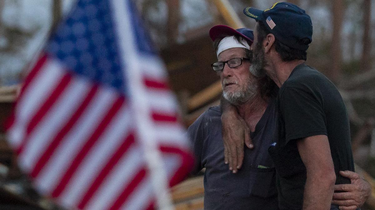 Carl Kuhn, 56, kisses his friend, Mickey Fox, 61, on Oct. 20, 2018, next to what remains of the trailer Fox and his wife rode out Hurricane Michael in. Kuhn pulled the Foxes from the ruins of their home in Callaway, Florida, during the eye of the storm.