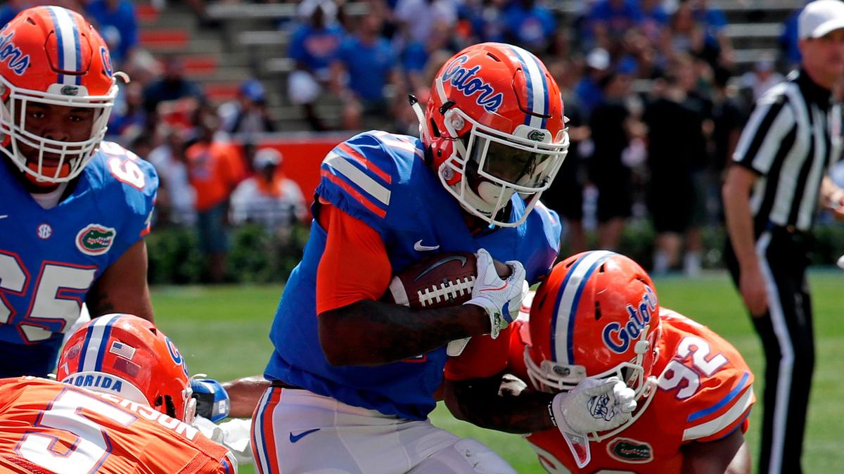 Florida Kadarius Toney, center, runs for yardage past defensive back CJ Henderson, left, and defensive lineman Jabari Zuniga (92) during an NCAA spring college football intrasquad game, Saturday, April 14, 2018, in Gainesville, Fla. (AP Photo/John Raoux)