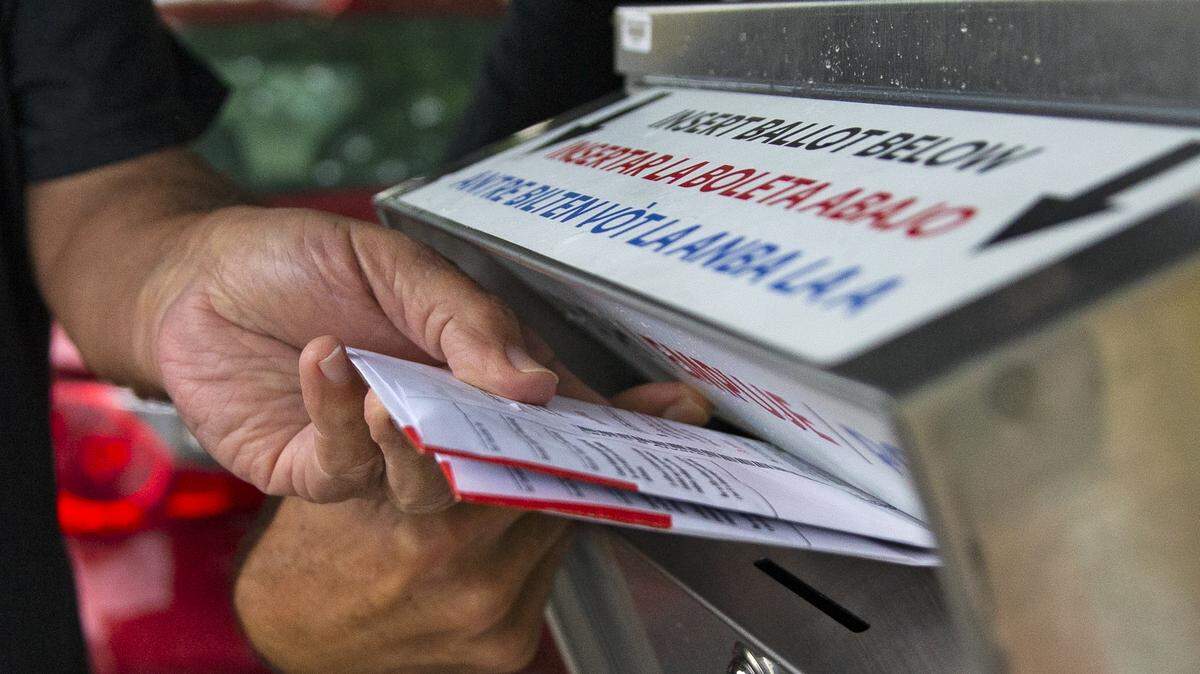 A polling worker deposits a ballot after collecting from a citizen on first day of early voting for the general election at Shenandoah Branch Library located at 2111 SW 19th St. on Monday, October 19, 2020, in Miami, Florida.