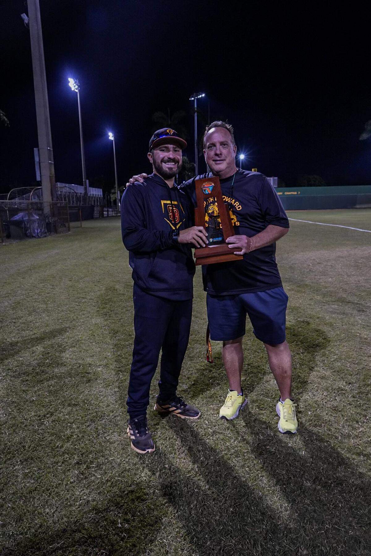 South Broward baseball coach Antonino Schembari (left), seen here with Bulldogs’ athletic director Lee Bray (right), led the Bulldogs to their first ever regional playoff win.