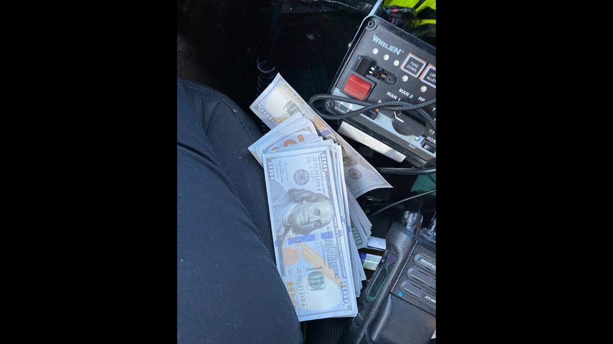 A stack of fake $100 bills is set by the center console of a Monroe County Sheriff’s Office patrol car Thursday, May 11, 2023.