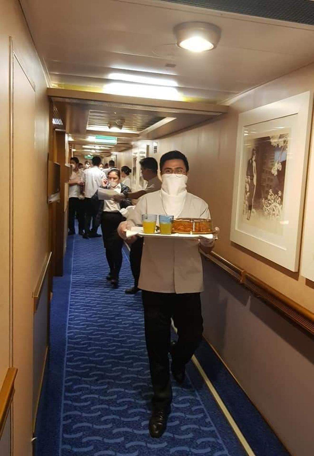 A crew member on the Costa Luminosa cruise ship delivers a meal to a passenger cabin. Passengers are confined to their cabins after several people tested positive for COVID-19 after disembarking.