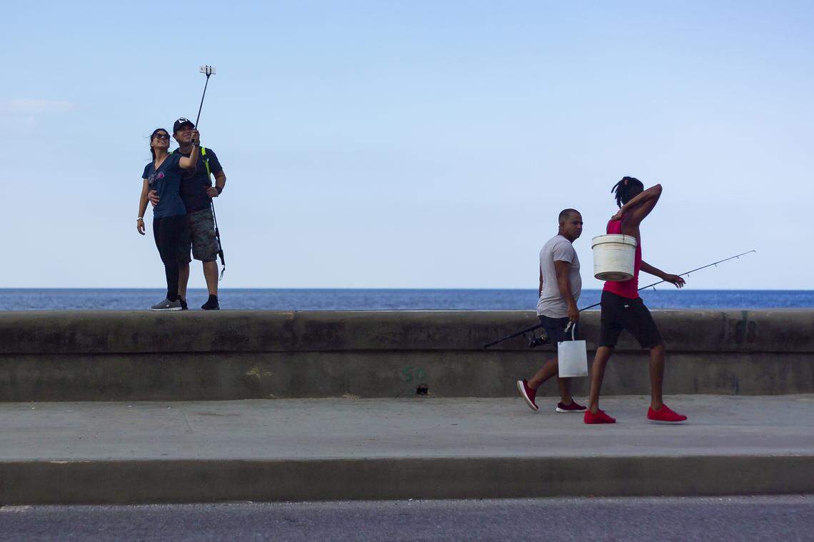 Tourists take selfies along the Malecón.