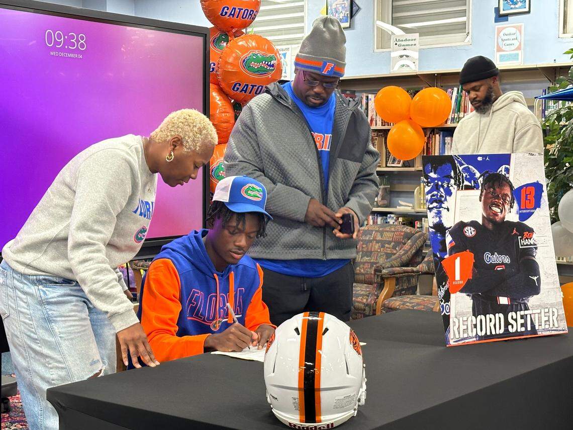 Miami Booker T. Washington’s Ben Hanks III signs his letter of intent with the University of Florida on Wednesday, Dec. 4, 2024 with his parents at his side during a ceremony at Booker T. Washington High School in Miami, Fla.