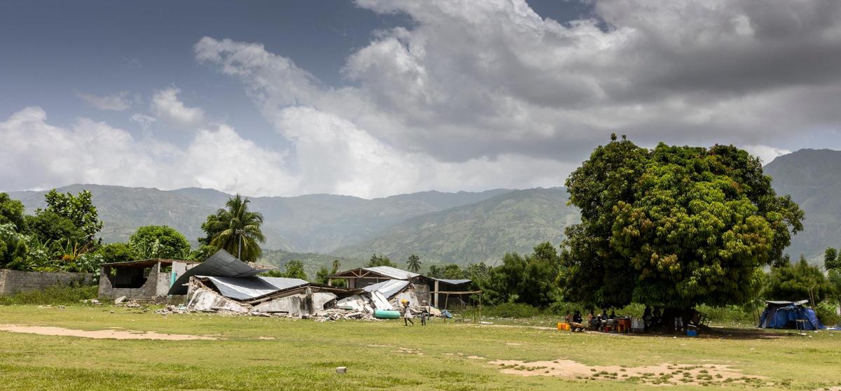 People take shelter on Monday, Aug. 23, 2021, under a mango tree next to what used to be a nightclub in Maniche, a town in southwestern Haiti devastated by the Aug. 14 earthquake.