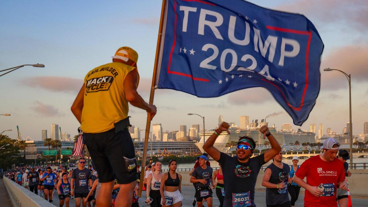 A runner shares his opinion as Chaunce O’Connor, 41, left, cheers on runners during the Life Time Miami Marathon while heading towards South Beach on Sunday, January 28, 2024 in Miami, Florida