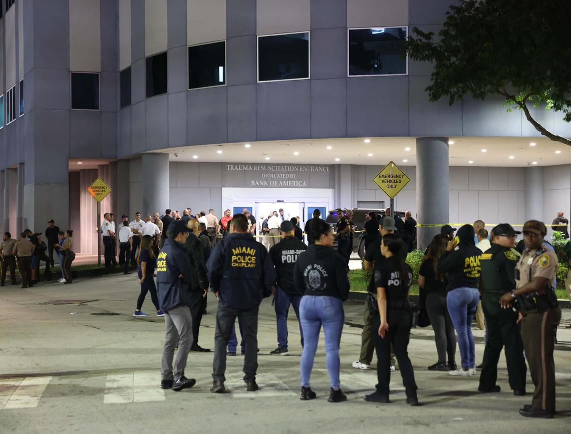 Police officers and other officials stand outside the Ryder Trauma Center after a Miami-Dade police officer was shot on Monday, Aug. 15, 2022.