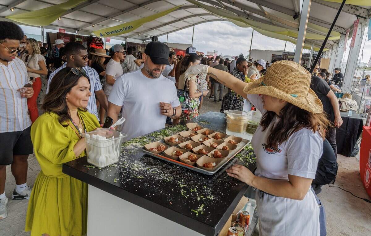 Sasha Soyka sprinkles cheese on top of meatballs at the Andiamo Brick Oven Pizza booth during the Grand Tasting Village, SoBe Wine & Food Festival, in Miami Beach, on Feb. 22, 2025.