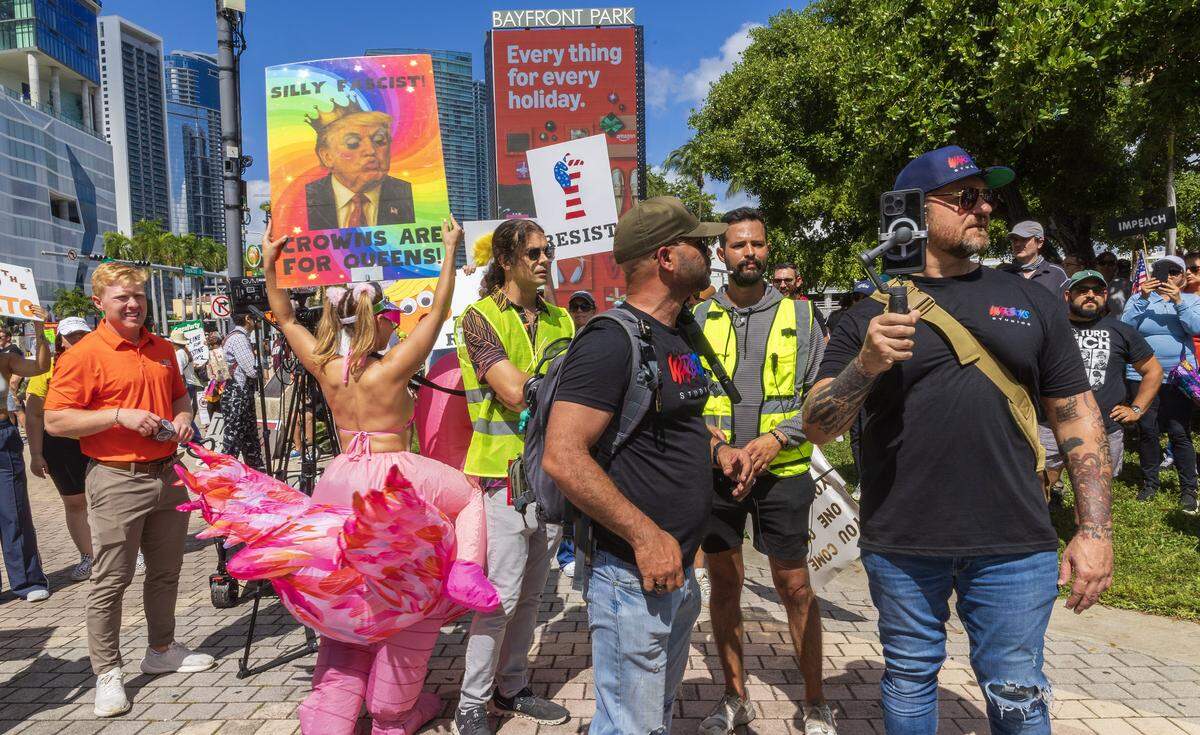 Event security follow former Proud Boy leader Enrique Tarrio (center) as he walked among protesters at the “No Kings” anti-Trump demonstration in downtown Miami. 