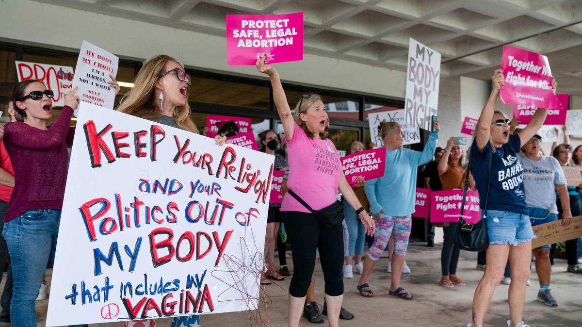 Protesters carry signs and listen to speakers as they demonstrate in front of the Paul G. Rogers Federal Building and U.S. Courthouse on May 3, 2022, in West Palm Beach, Florida. A draft opinion suggests the U.S. Supreme Court could be poised to overturn the landmark 1973 Roe v. Wade case that legalized abortion nationwide.