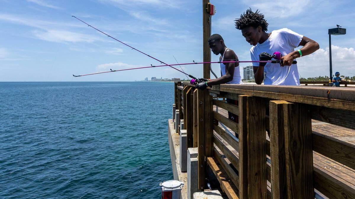 Jatari Johnson y Ethan McNeal pescan en el muelle durante una excursión del campamento de verano Root Collectives en Dania Beach Pier, en Dania Beach,  Florida, el 15 de julio de 2023.