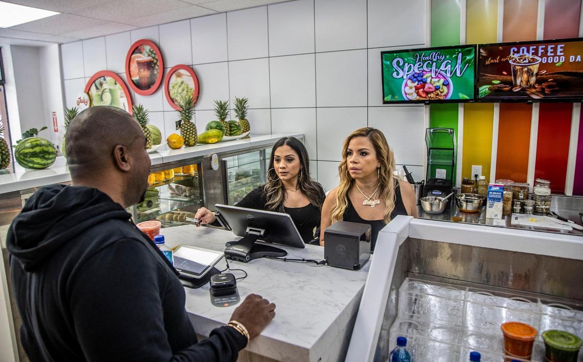 Staff member Perla Rincon, left, and owner Neri Santiago talk with her husband, N.O.R.E., at the Juicy Juice Bar.