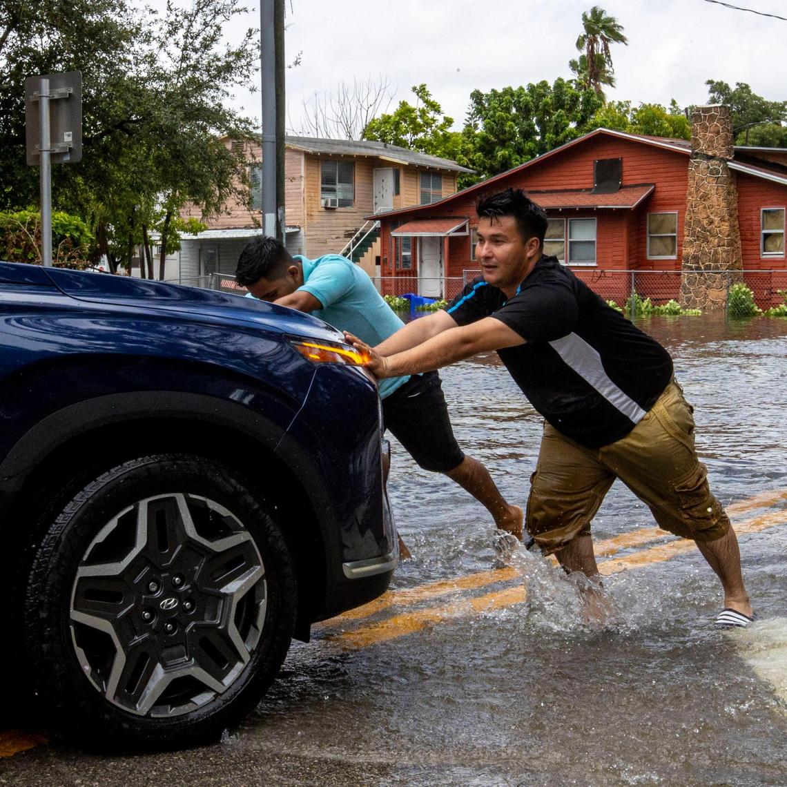 Two motorists push their vehicle out of flood waters near Southwest Fourth Street and Eighth Avenue in the Little Havana neighborhood of Miami, Florida, on Saturday, June 4, 2022.