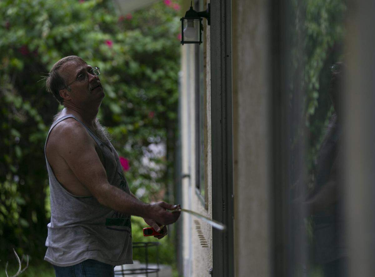Colin Johnson, 51, measures a window at his father’s Vero Beach home. Johnson’s father, Larry, died unexpectedly Thursday.