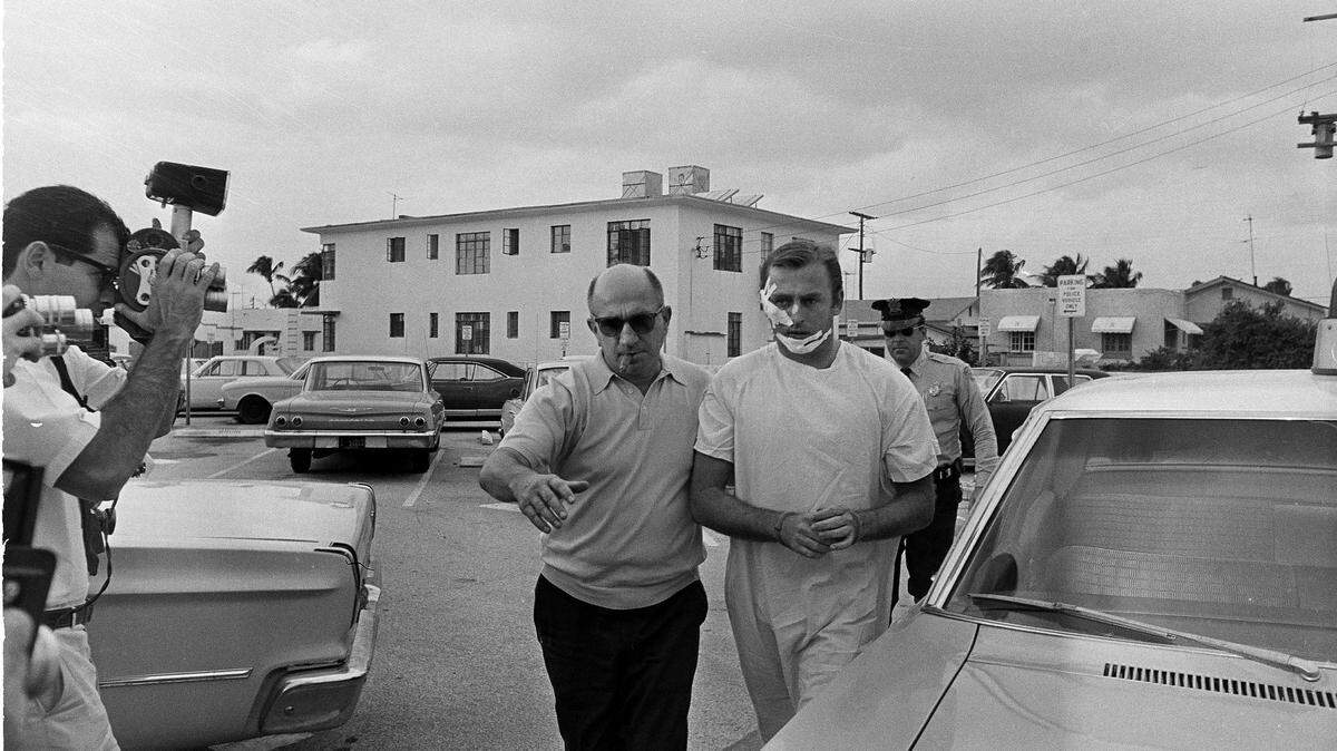 Jack “Murph the Surf” Murphy is escorted to the Miami Beach Police station by detectives Jan. 28, 1968, after he was arrested with three other men for armed robbery. Police said Murphy cut his face while trying to escape through a glass door.