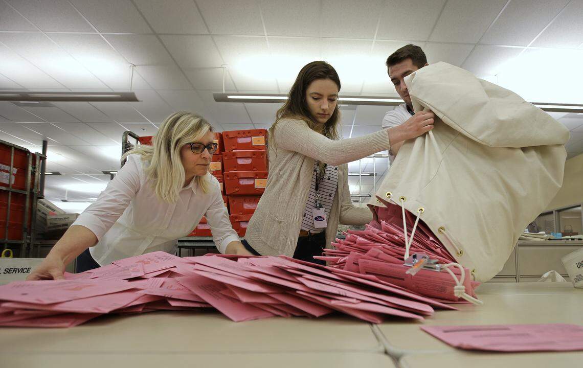 In this June 5, 2018, file photo, election workers Heidi McGettigan, left, Margaret Wohlford, center, and David Jensen, unload a bag of ballots brought in from a polling precinct to the Sacramento County Registrar of Voters office in Sacramento, California, one of a number of growing U.S. locales that are conducting elections almost entirely by mail.