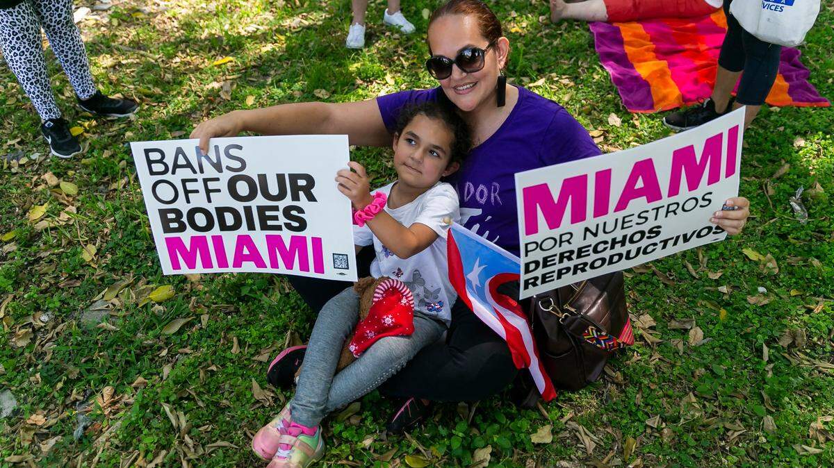 Leslie Rodríguez y su hija, Gianna Vélez, de 5 años y de North Miami Beach, sostienen carteles mientras asisten a una manifestación en el Ives Estates Park de Miami, Florida, el sábado 14 de mayo de 2022. La protesta fue en oposición al proyecto de opinión filtrado de la Corte Suprema federal que pretende anular el caso Roe vs. Wade, eliminando el derecho libre de las mujeres al aborto.
