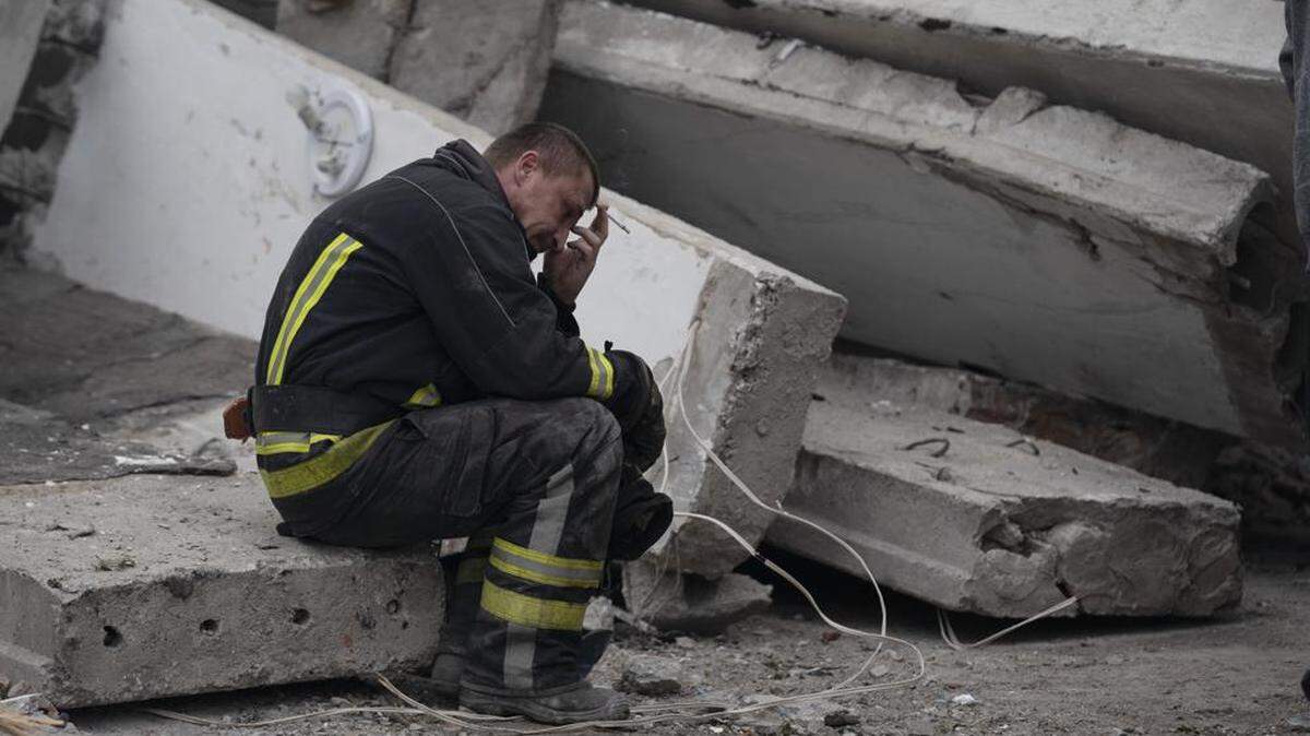 A rescue worker takes a break on Sept. 28 as he sits on the debris at the scene where a woman was found dead after a Russian attack that heavily damaged a school in Mykolaivka, Ukraine. 