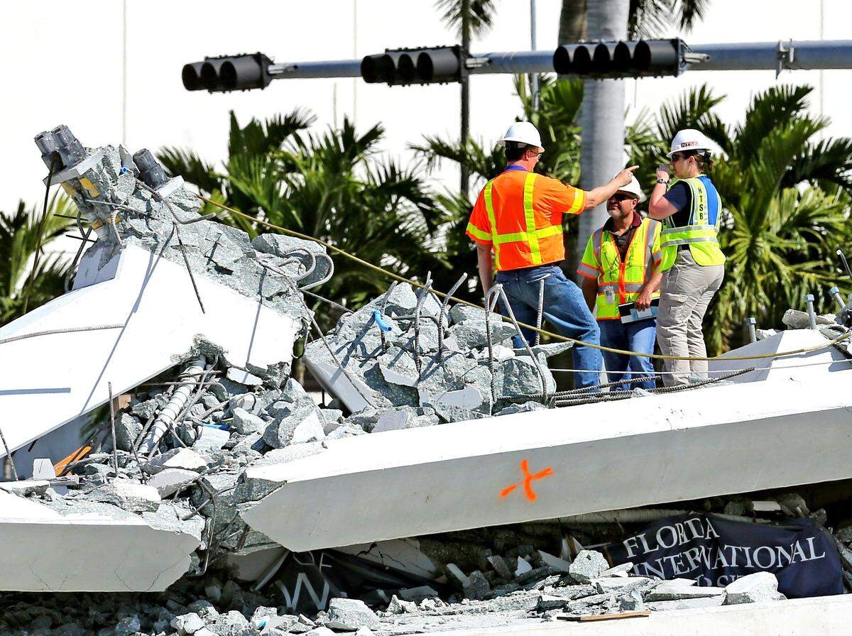 NTSB inspectors stand along a section of the collapsed FIU bridge on March 16, 2018. The bridge collapsed a day earlier on cars that were traveling along Tamiami Trail. Six people were killed.