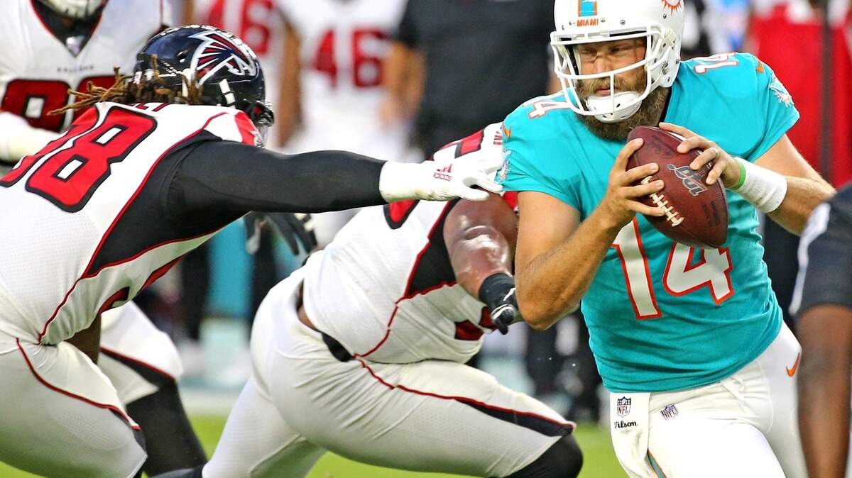 Miami Dolphins quarterback Ryan Fitzpatrick (14) tries to escape Atlanta Falcons Takkarist McKinley (98) in the first quarter at Hard Rock Stadium in Miami Gardens, Florida, Thursday, August, 8, 2019.