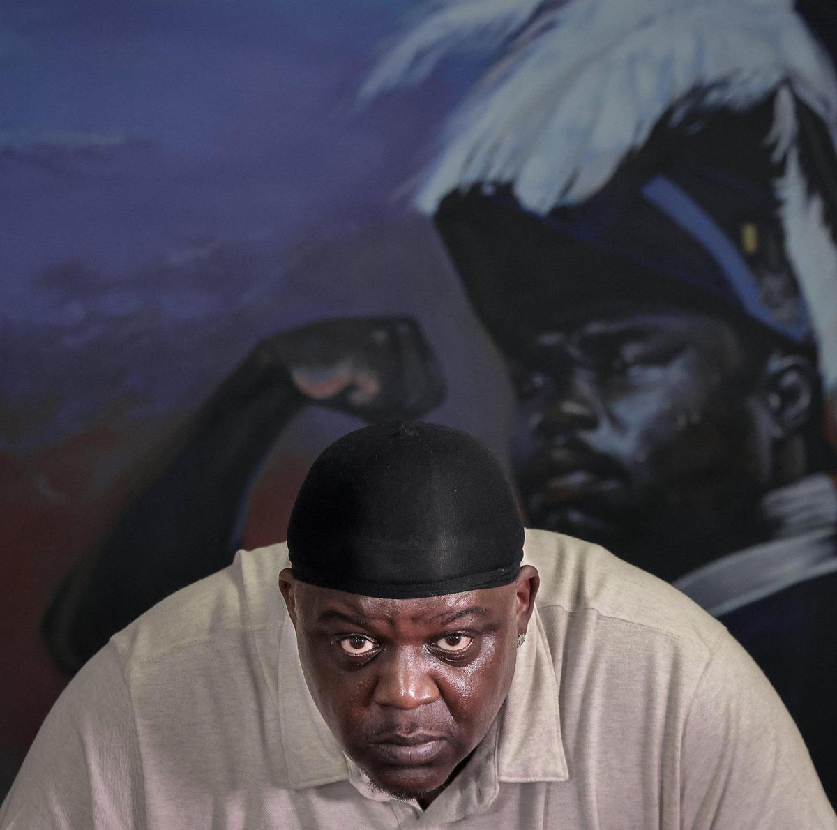 Muralist Addonis Parker, who opened his exhibit and Still We Rise in Opa-locka, is photographed among his artwork dealing with Black identity, liberation, and strength at his Miami studio.