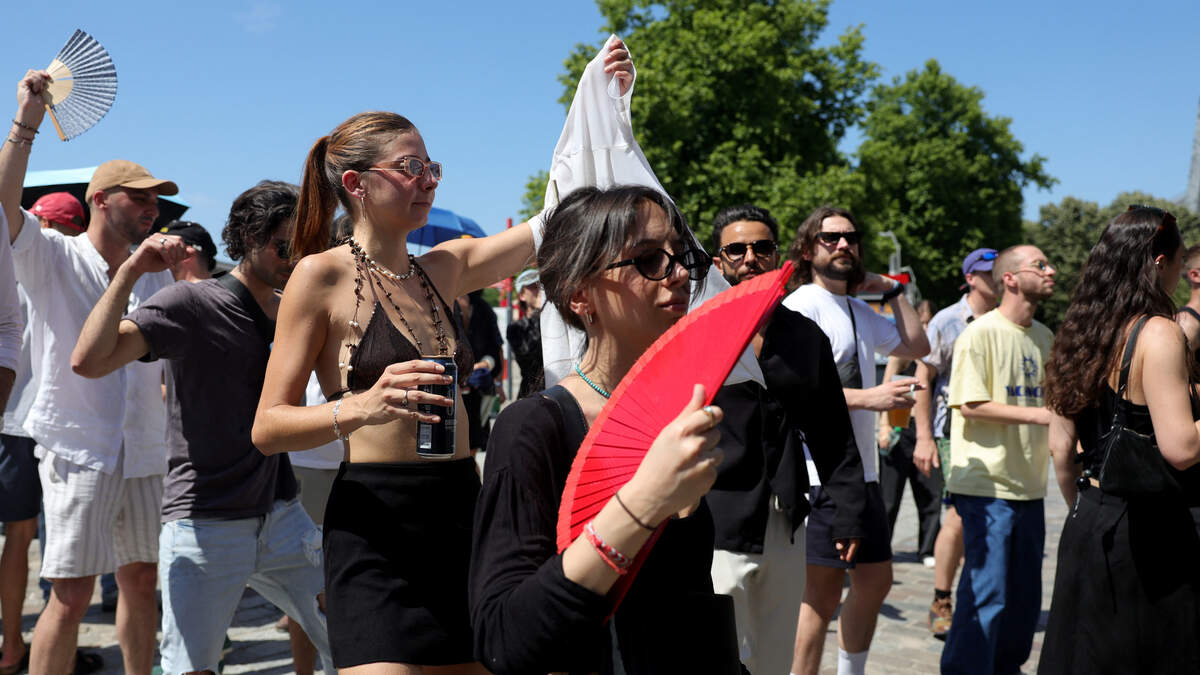 Dancers cool off with fans as they take part in the “Fete de la Musique” (French midsummer Festival of Music) during a heatwave in Paris on June 21, 2025.