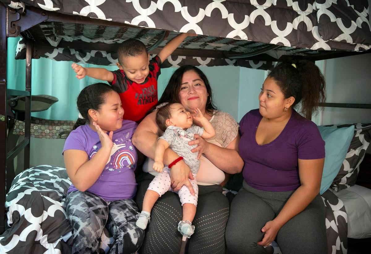 Lorena Torrente con sus cuatro hijos, (de izq. a der.) Noelis de 10 años, Rafael de tres, Melissa de nueve meses y Noelia de 15 años. Torrente se quedó sin hogar durante la pandemia y necesita una vivienda para ella y sus hijos. La familia está siendo asistida por Miami Rescue Mission, pero espera volver a tener un lugar propio. Los niños también necesitan ropa y material escolar. La familia aparece en una de las instalaciones de alojamiento temporal de Miami Rescue Mission, donde vivieron durante un breve periodo de tiempo antes de ser colocados en otra instalación que comparte con otras dos familias.