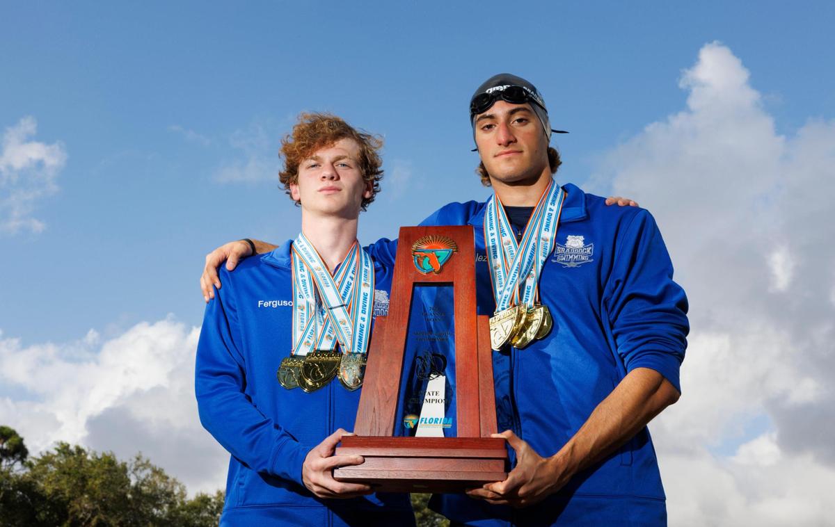 Dylan Ferguson, left, and George Gonzalez, seniors at Braddock on the boys swim team, pose with their medals and the state champion trophy for the All-Dade Players of the Year photo on Tuesday, Dec. 17, 2024, at AD Barnes Park in Miami.
