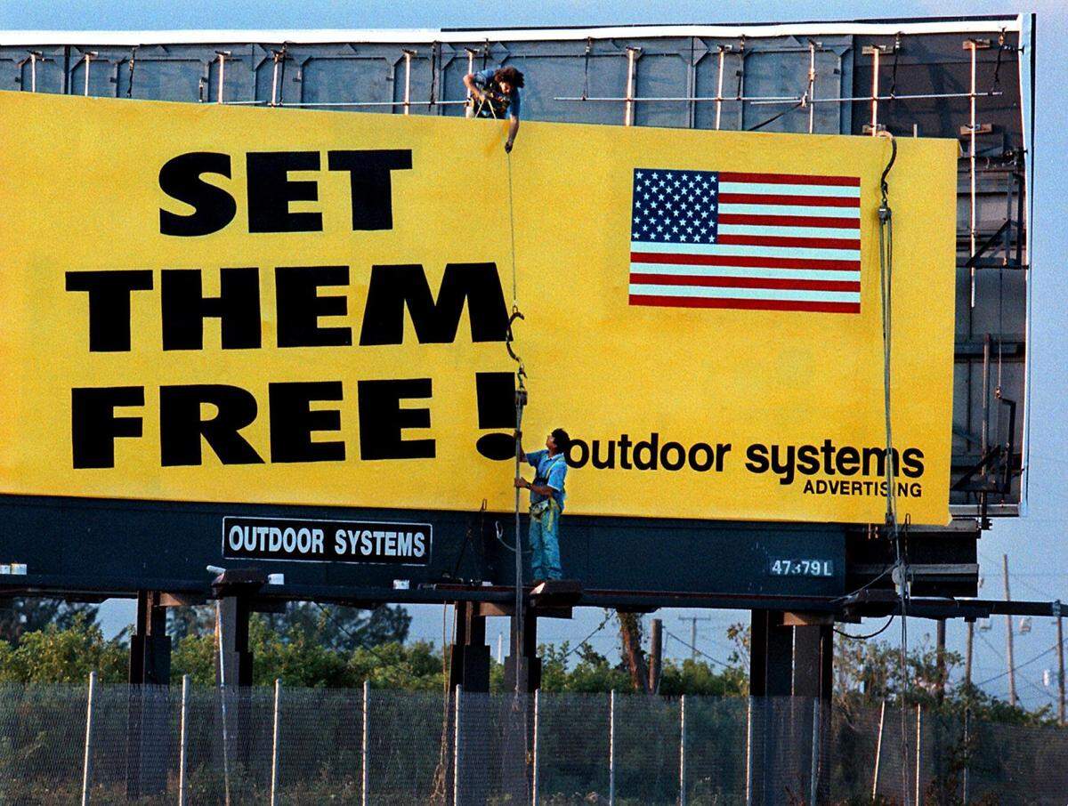 In 1999, Outdoor Systems Advertising employees Sebastian Nasselo, top, and Armando Cacciavillani lower a rope holding a platform they used to paint a billboard referring to three American soldiers captured by Yugoslav forces. Truly Nolan and Outdoor Systems had the sign erected together. It was in Pembroke Park, on southbound Interstate-95 just south of Hallandale Beach Boulevard, near the Broward-Miami-Dade County line.