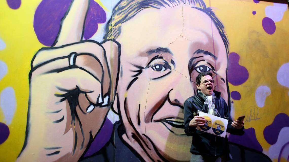 A supporter of Rodolfo Hernandez, the presidential candidate dubbed “Colombia’s Trump,” stands in front of a mural of the candidate.