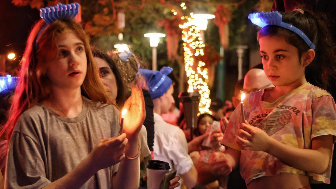 Girls light candles during the lighting of the menorah at Lincoln Road and Euclid Circle in Miami Beach on Thursday.