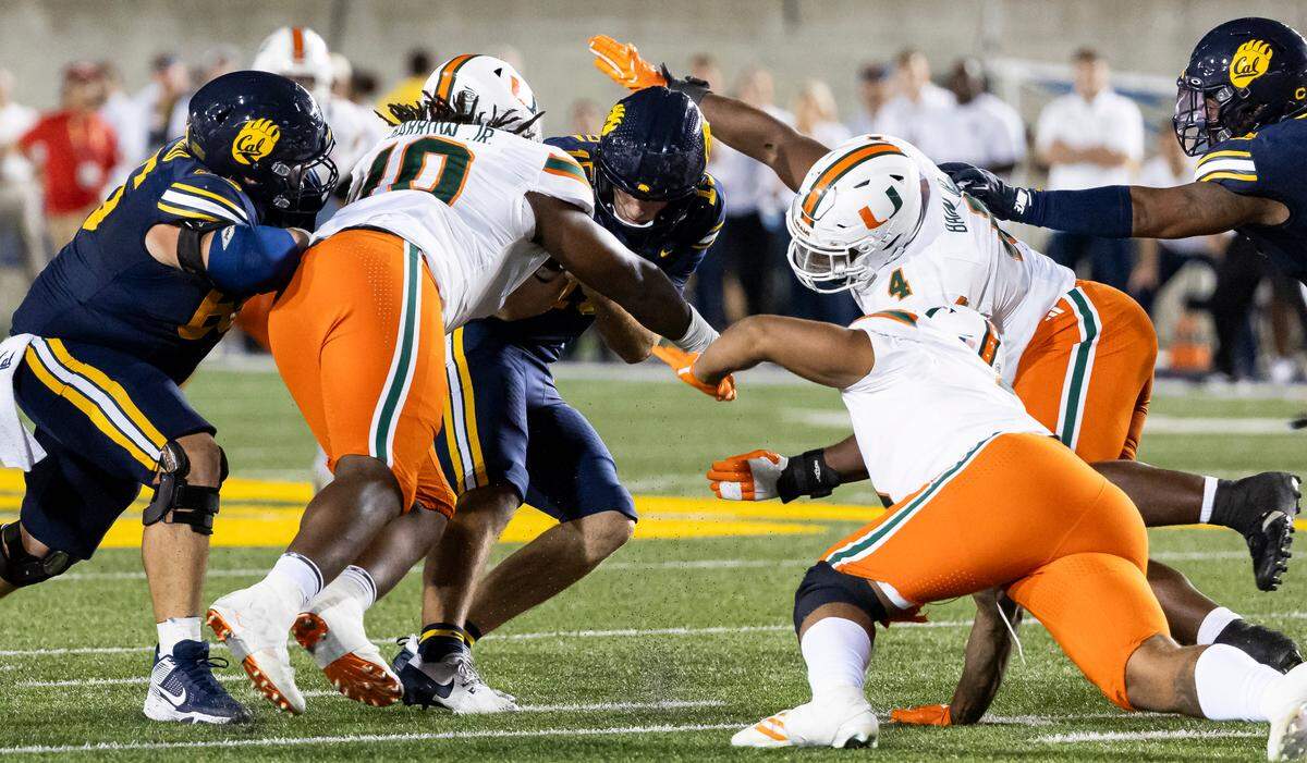 Miami Hurricanes defensive linemen Simeon Barrow Jr. (10) and Rueben Bain Jr. (4) work to tackle California Golden Bears quarterback Fernando Mendoza (15) in the second half of their NCAA college football game at the California Memorial Stadium on Saturday, Oct. 5, 2024, in Berkeley, Calif.