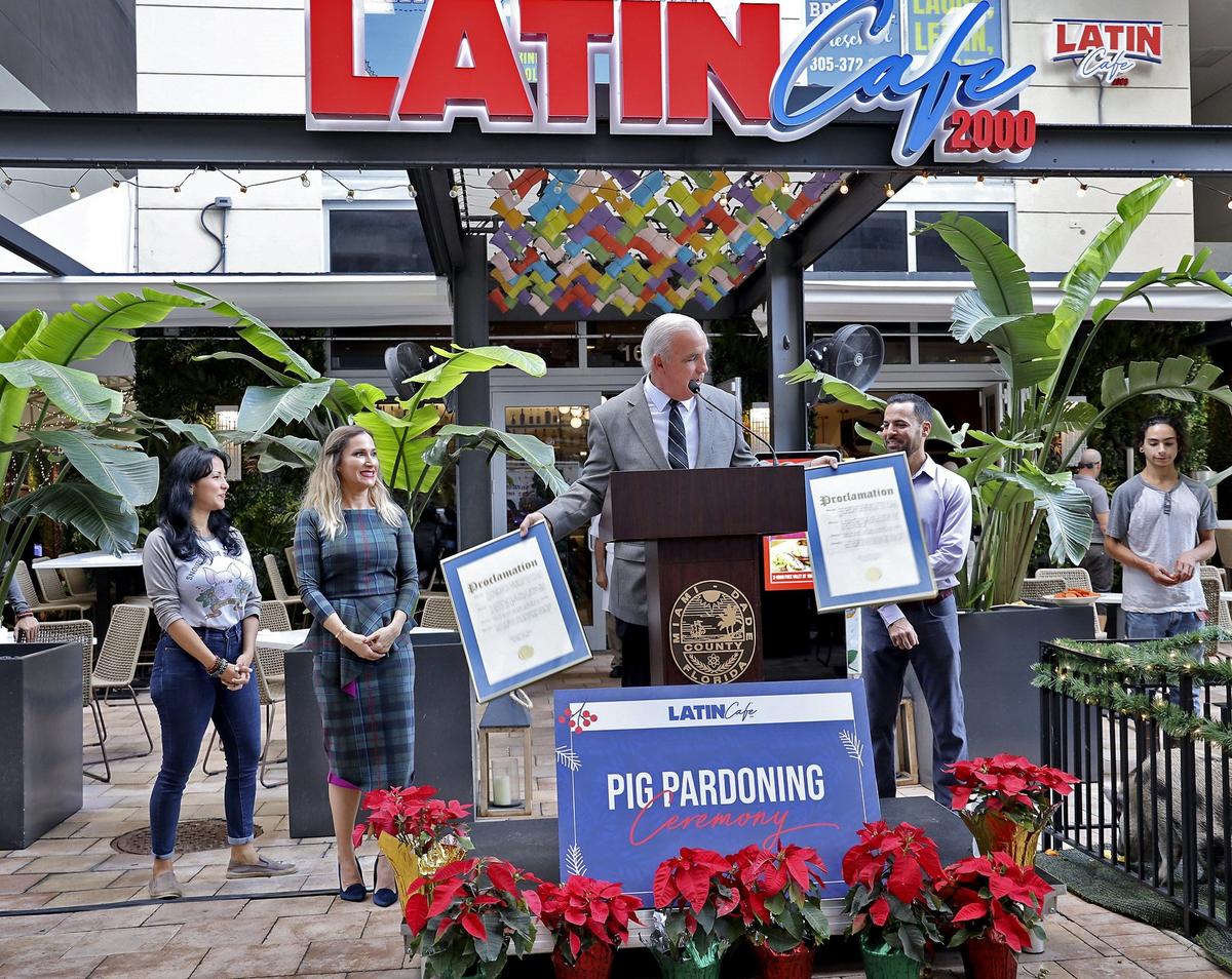 Mayor Carlos Gimenez, center, holds the proclamations for “Petra” and “Peppa” (black), the two lucky pigs that he he pardoned in the second annual “Pig Pardoning Ceremony” at Latin Cafe 2000 Brickell.