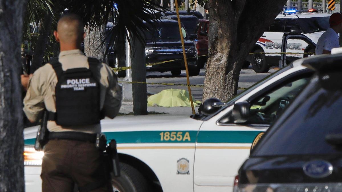 A body lies on the sidewalk near the intersection of Northeast Second Avenue and 119th Street where a Miami-Dade Police officer was injured after a police-involved shooting in North Miami Saturday afternoon.