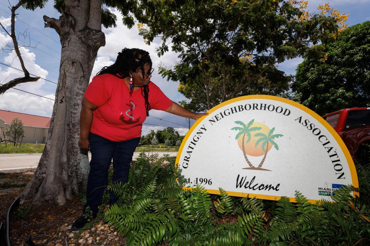 Joyce Brown, present of the Gratigny Homeowners Association, poses with the neighborhood sign during the day on Tuesday, July 22, 2025, in the Gratigny neighborhood in Miami.